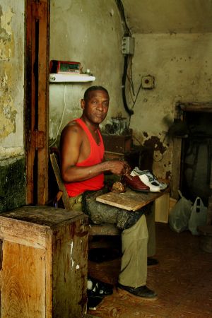 SHOE REPAIR MAN IN A VERY SMALL WORK SPACE.